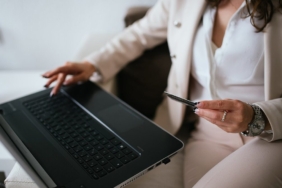 Evde dizüstü bilgisayardan internet alışverişi yapan kişi