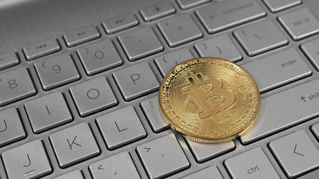 Dizüstü bilgisayar klavyesi üzerinde duran Bitcoin temsili madeni para