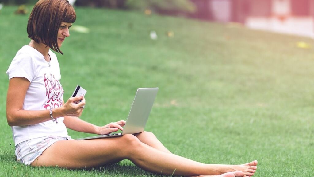 Açık havada dizüstü bilgisayardan internet alışverişi yapan kadın