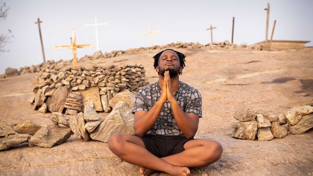 Tepede oturarak meditasyon yapan kişi