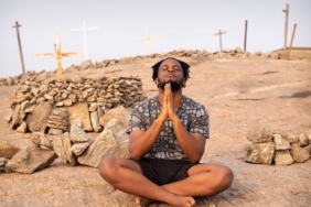 Tepede oturarak meditasyon yapan kişi